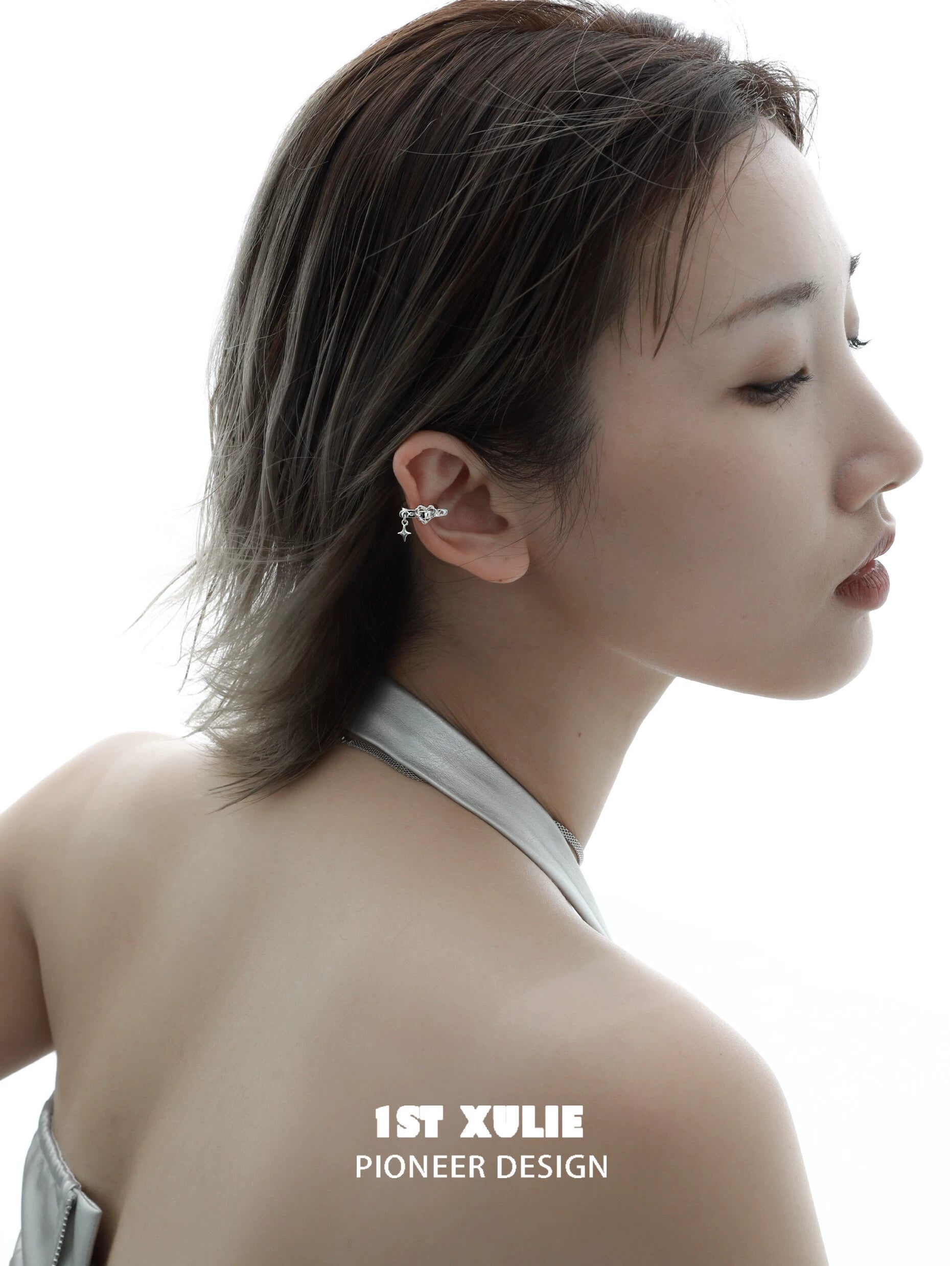 Model wearing edgy heart ear cuff from 1STXULIE with a stylish hairstyle and silver outfit