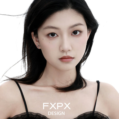 Young woman wearing bloody doll jewelry Y2K snake cross earrings in a minimalistic studio setting