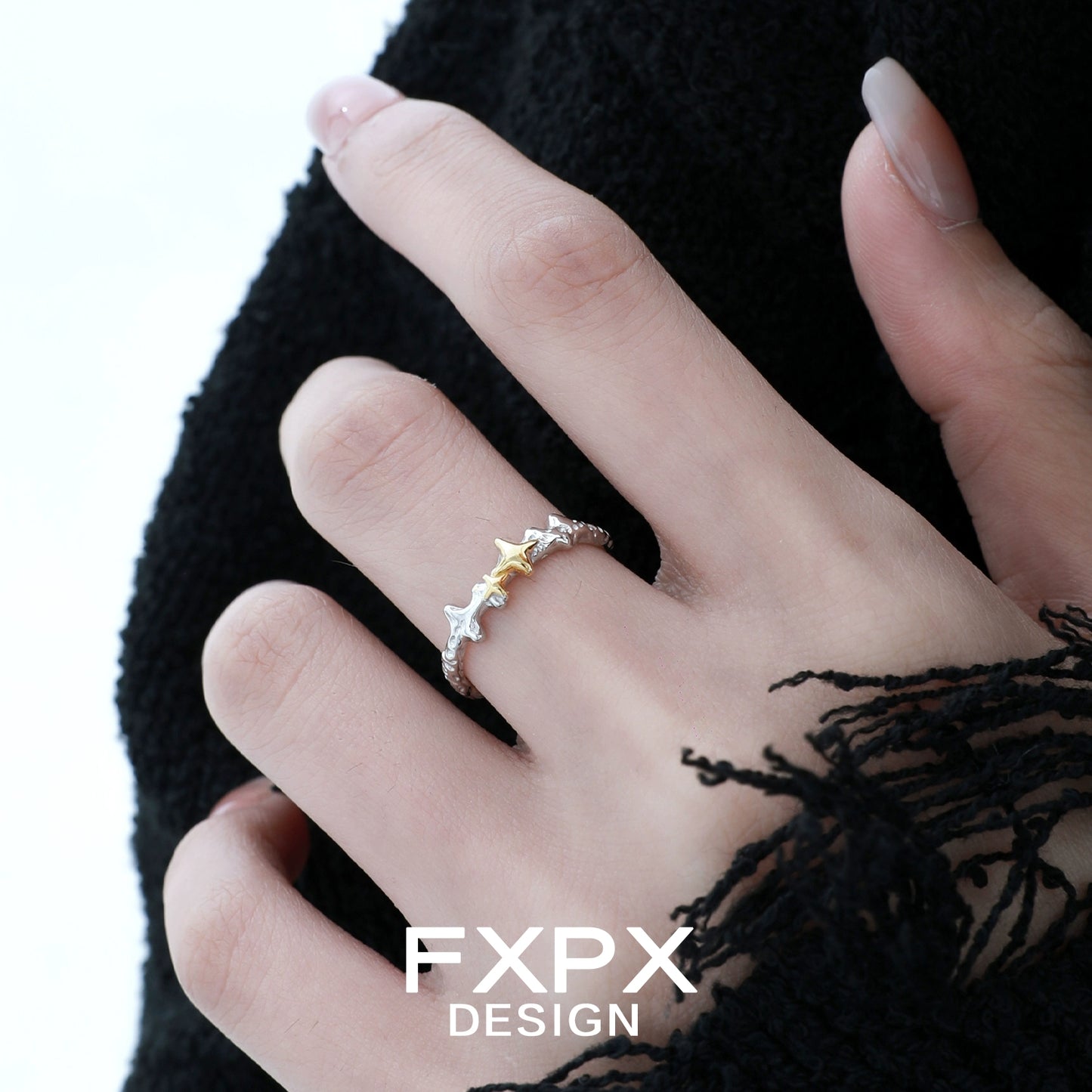 FXPX gold star ring on a hand with a stylish black outfit, featuring a unique design