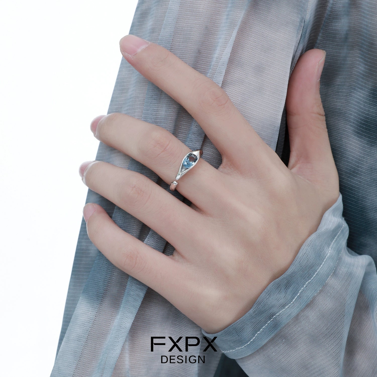 Elegant FXPX Iceland blue zircon ring displayed on a hand with stylish attire
