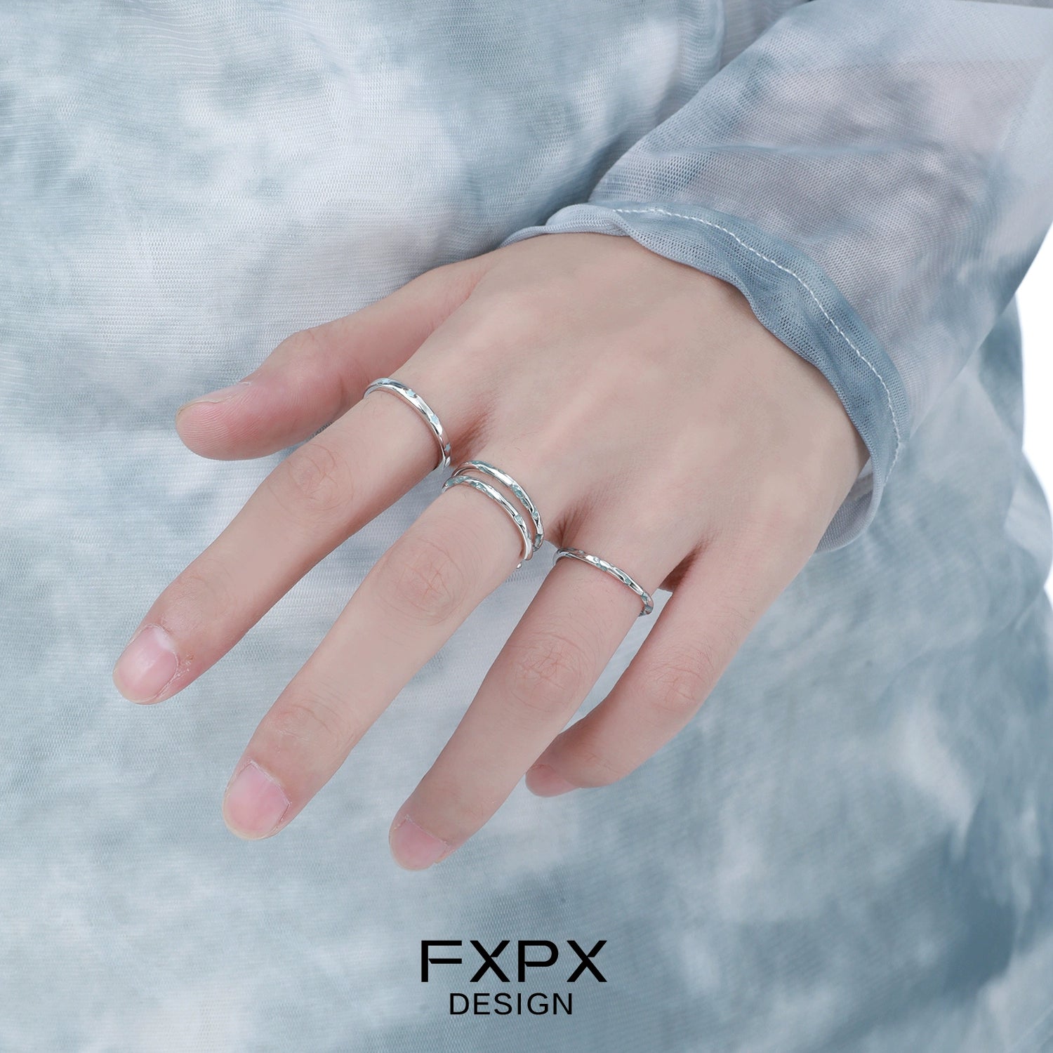 Three silver rings worn on a hand featuring the ocean breeze ring design for a stylish look