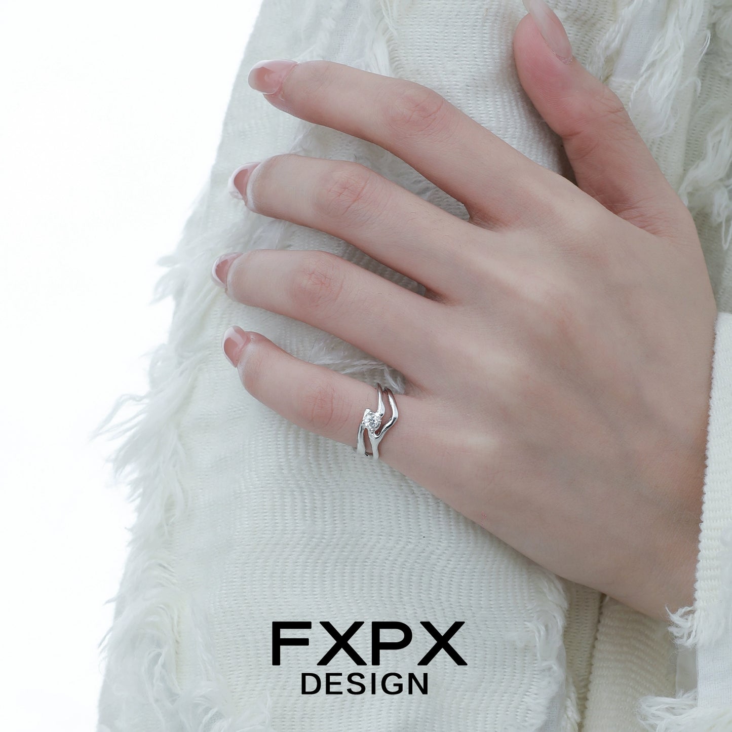 Stylish FXPX silver wave zircon ring displayed on a hand with textured white fabric background