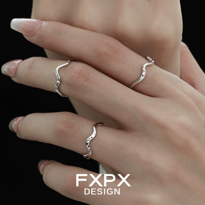 Three delicate wavy silver rings displayed on fingers, showcasing unique design by FXPX