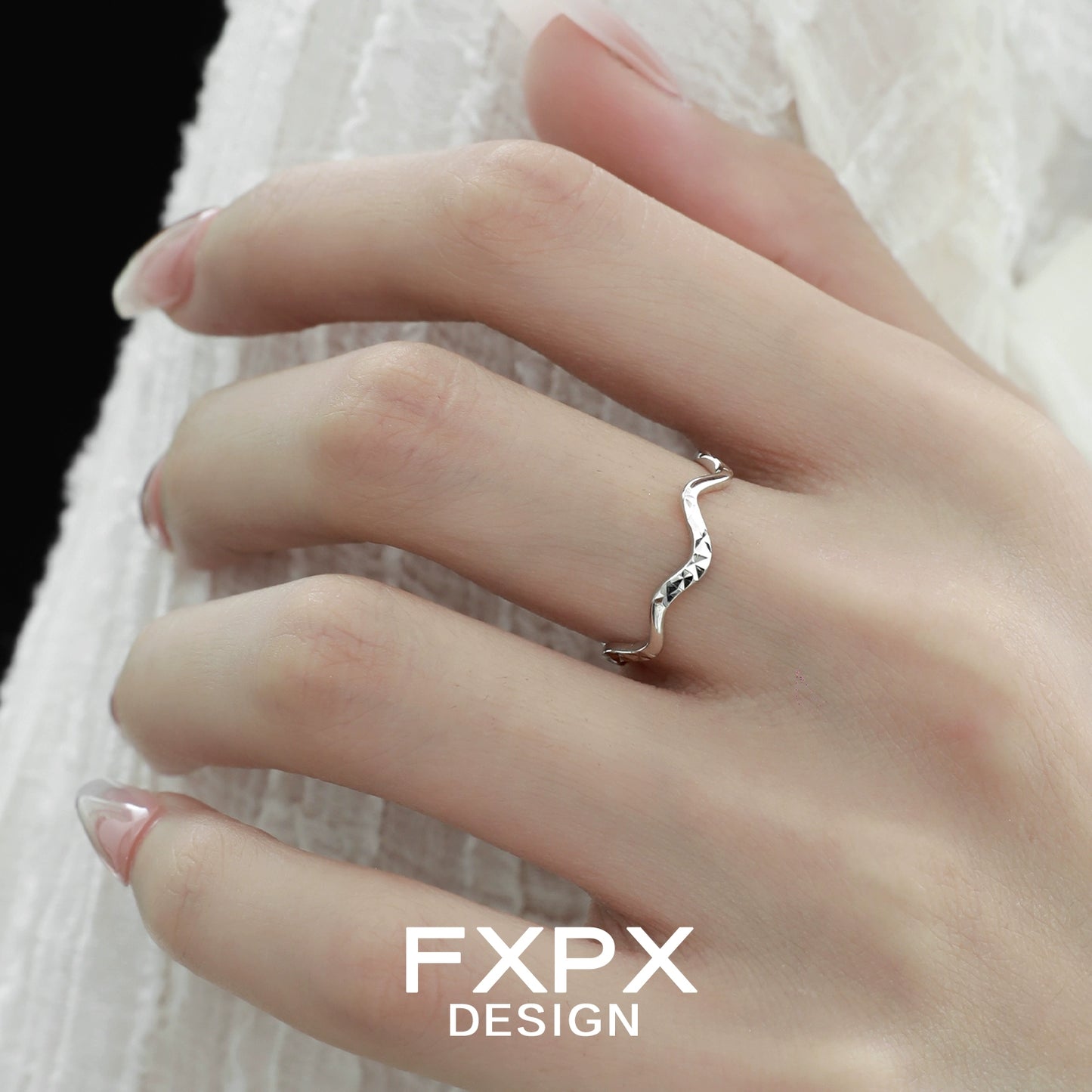 Elegant wavy silver ring showcased on a hand with manicured nails against a soft background