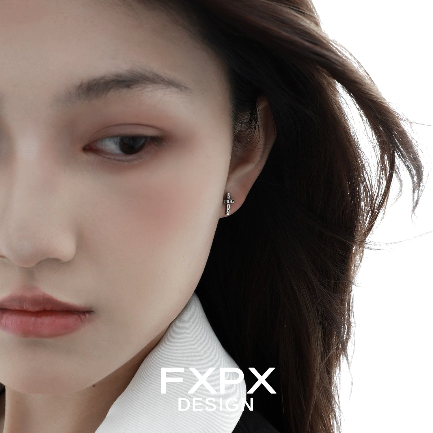 Close-up of Y2K punk cross earrings worn by a model with long hair and a stylish outfit