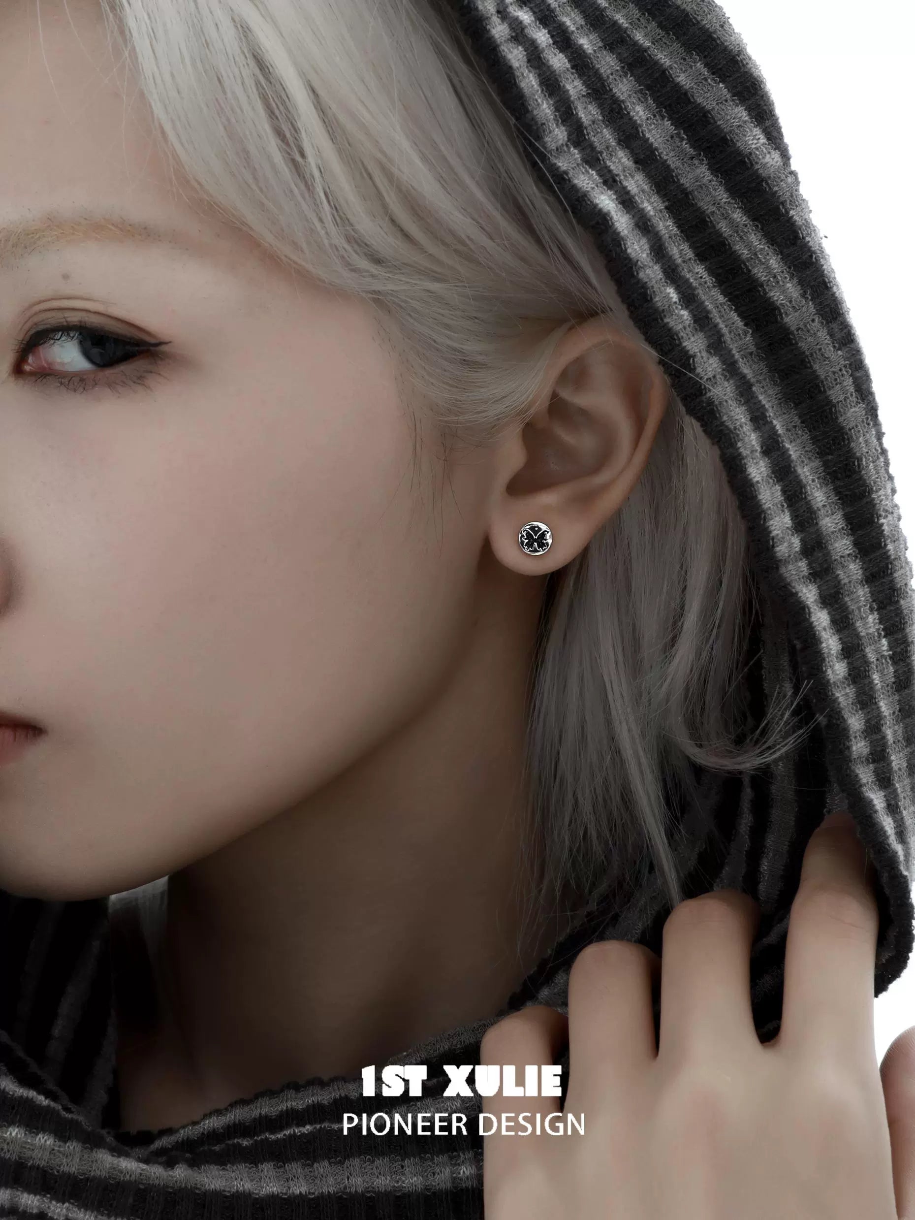 Gothic butterfly earrings displayed on a model wearing a hoodie with striking features