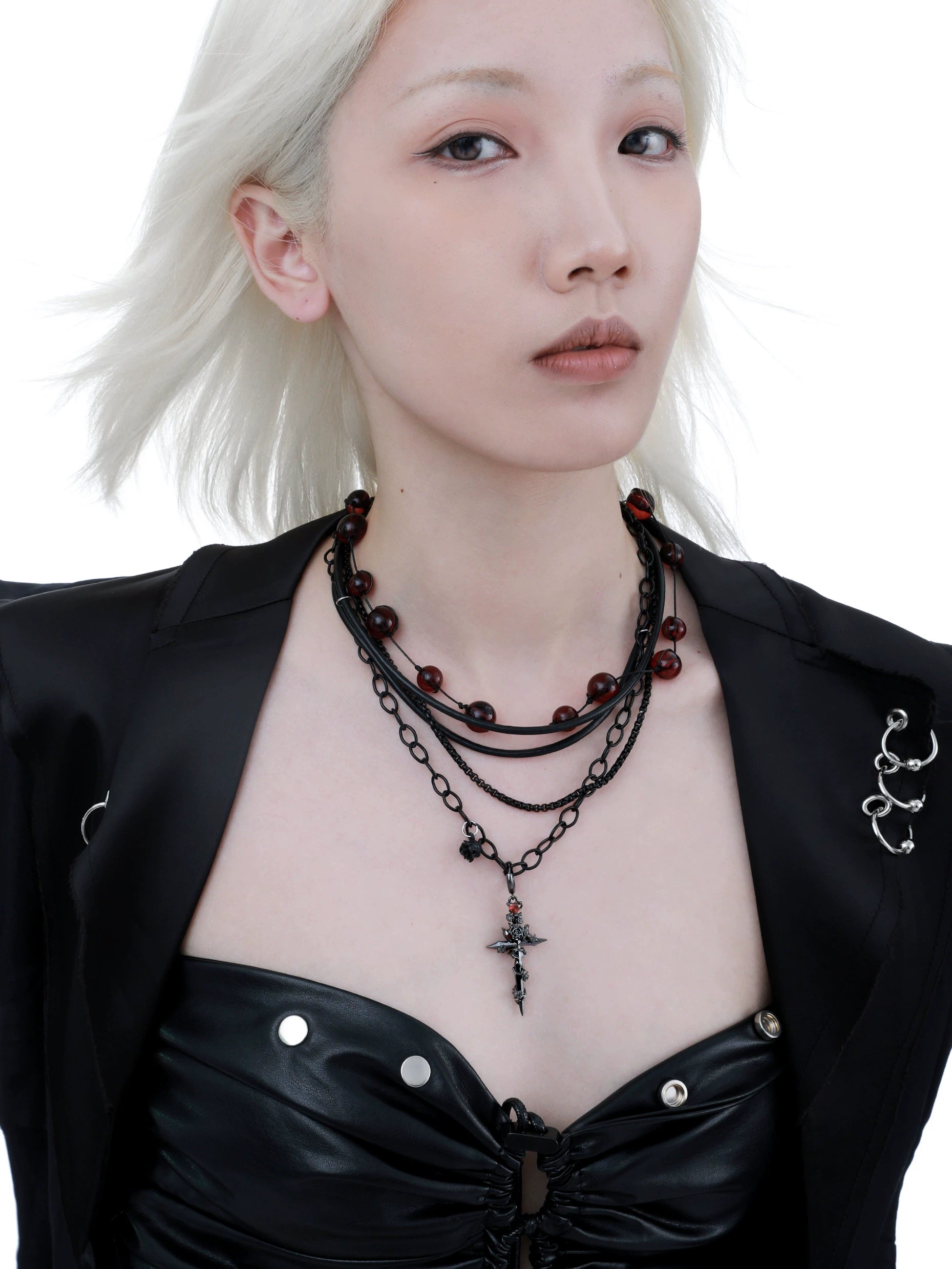 Gothic cross necklace featured on model with layered black chains and red beads for a striking look