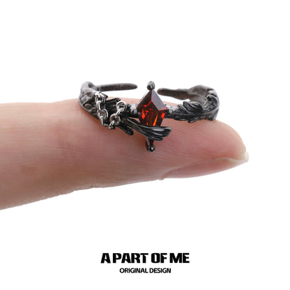 A gothic feather ring featuring a dark design with a red gemstone on a finger for a unique statement piece
