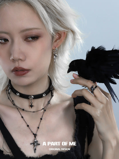 A gothic raven cross necklace worn by a model with a raven perched on her finger