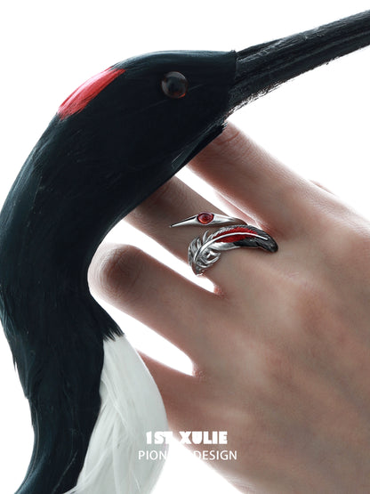 Gothic silver crane ring on a hand, featuring intricate design and red gemstone accents