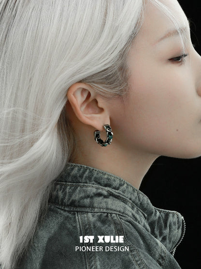Gothic venomous spirit earrings displayed on a model with silver hair and a dark jacket