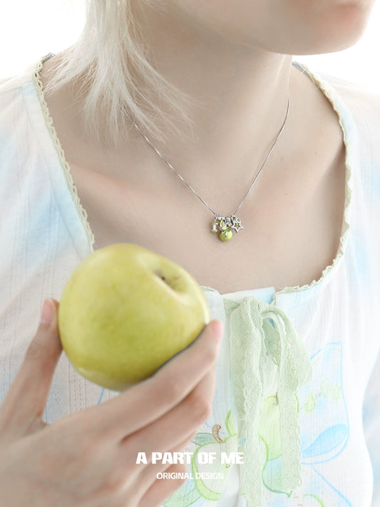 A PART OF ME green apple star necklace showcased on a model holding a green apple