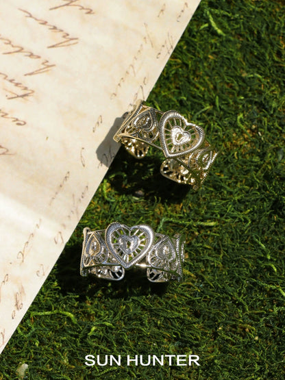 SUN HUNTER heart lock ring set in gold and silver with intricate detailing on a natural background