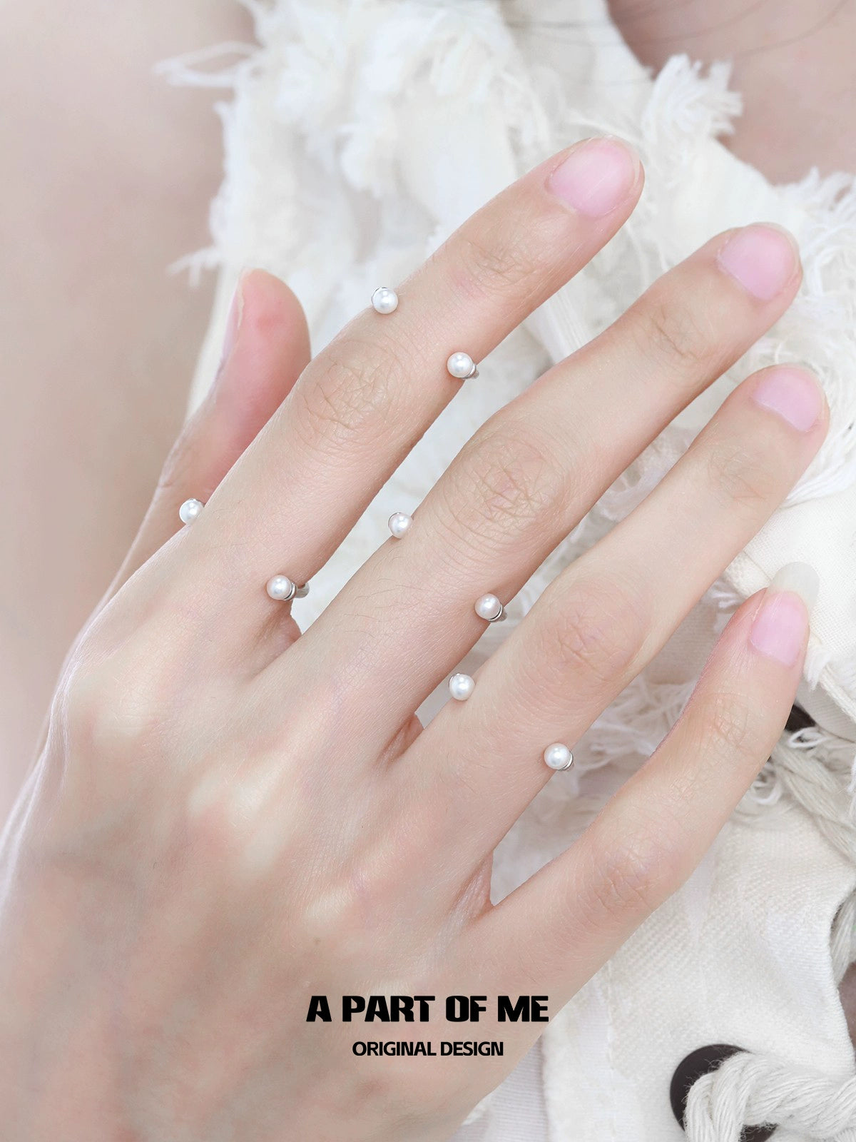 A minimalist design featuring a delicate minimal pearl ring on a hand with soft pink nails