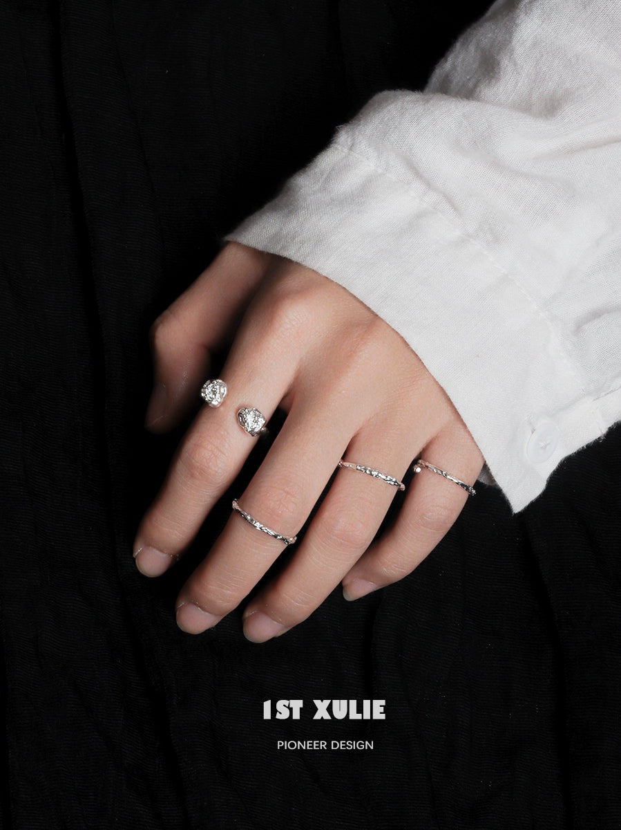 Two minimalist silver rings showcased on a hand with a white shirt, highlighting elegant simplicity
