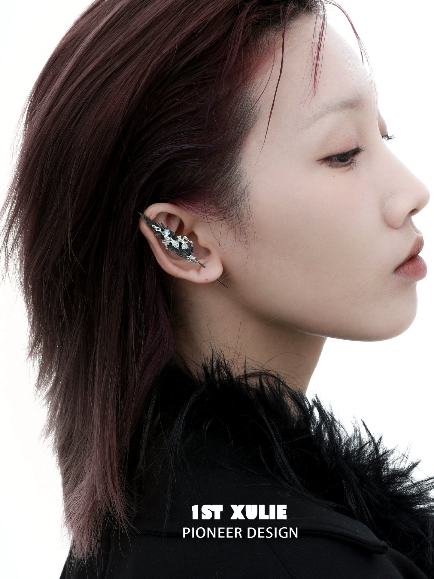 Unique mystic feather piercing earring designed by 1ST XULIE, showcased on a model's ear