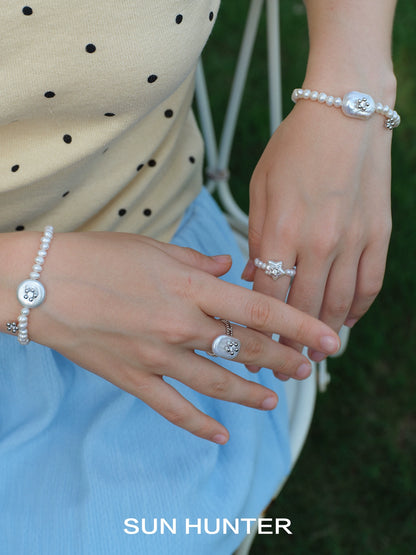 SUN HUNTER ocean memory pearl bracelet featured alongside stylish rings on a model's hand