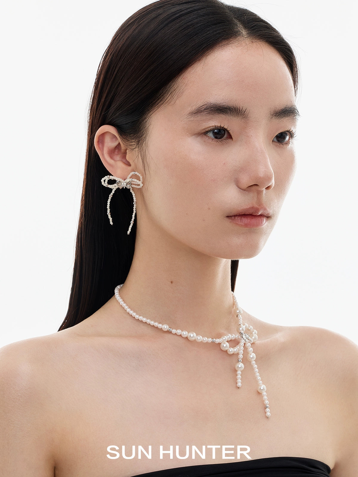 Elegant SUN HUNTER pearl bow ribbon earrings featured on a model showcasing a chic look