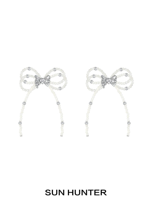 Elegant SUN HUNTER pearl bow ribbon earrings featuring sparkling accents for a stylish look