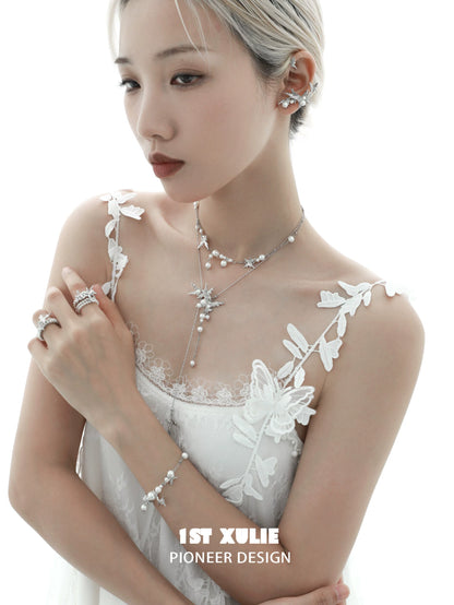 Elegant model wearing a pearl butterfly ring alongside matching jewelry pieces in a soft light