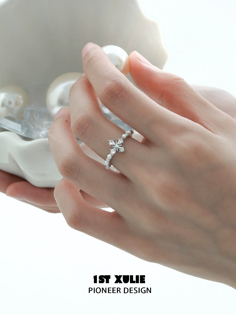 Elegant pearl cross silver ring showcased on a hand holding decorative pearls