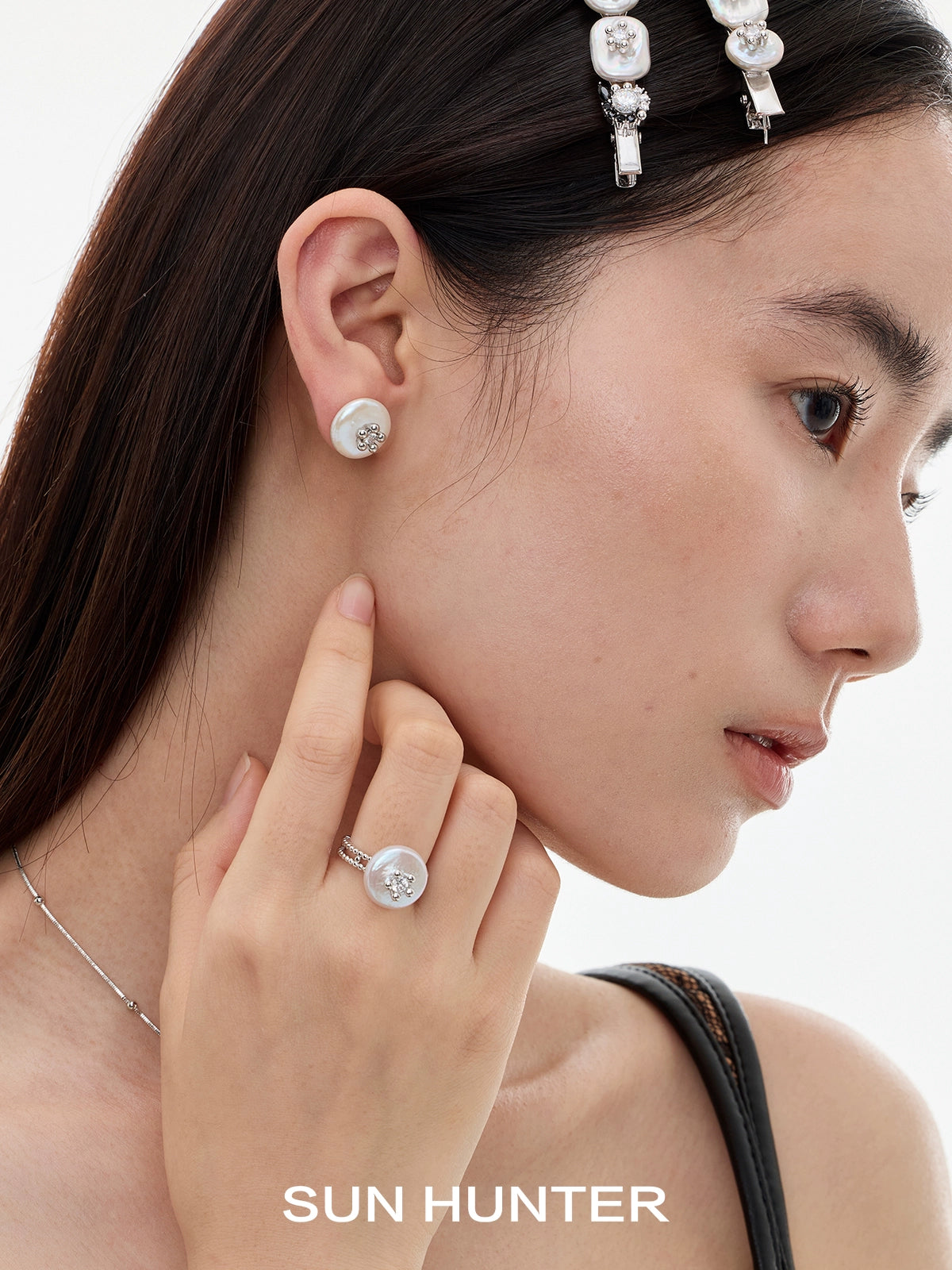 Elegant model wearing SUN HUNTER pearl riddle rings and matching pearl earrings for stylish accessory lovers