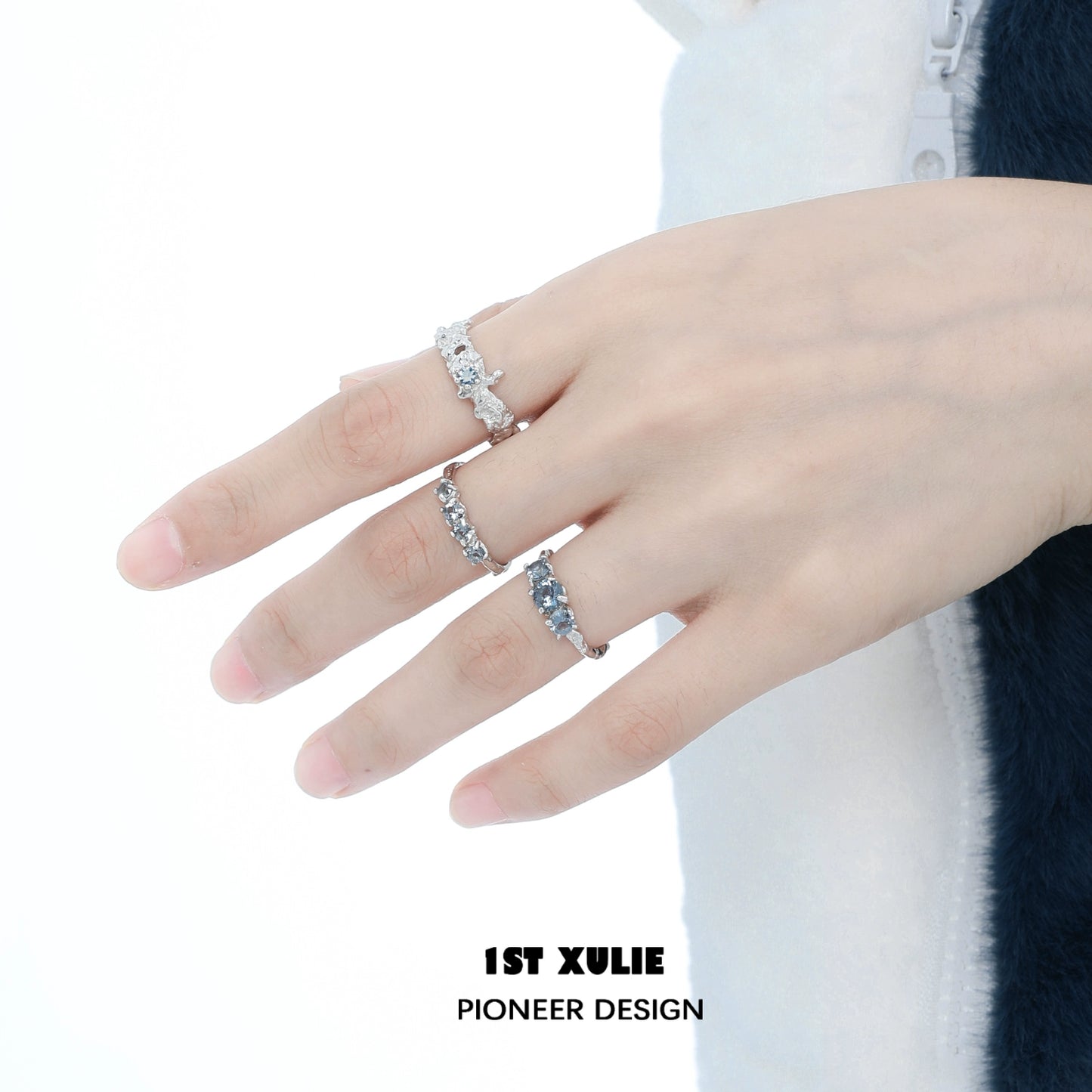 Three elegant rings worn on a hand, featuring the aurora glacier silver ring design