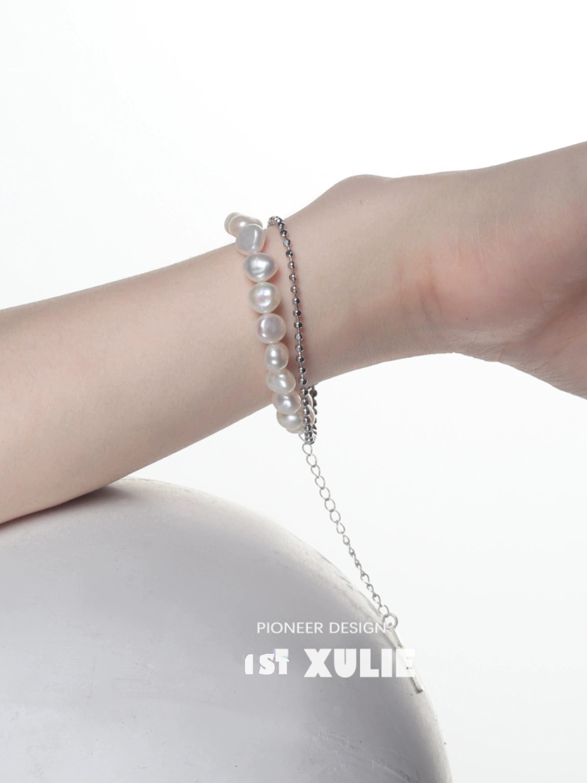 Baroque pearl silver bracelet elegantly worn on a wrist against a neutral background