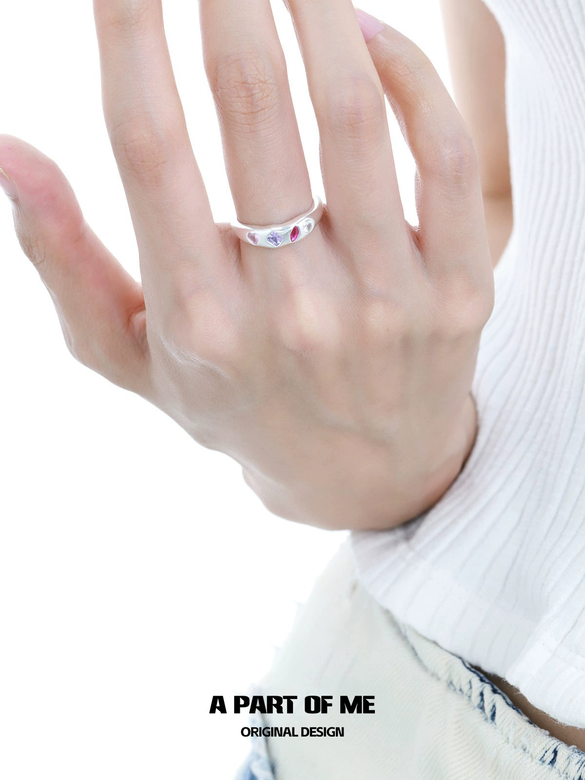 A hand wearing a rainbow zircon love ring featuring colorful stones for a unique and stylish look