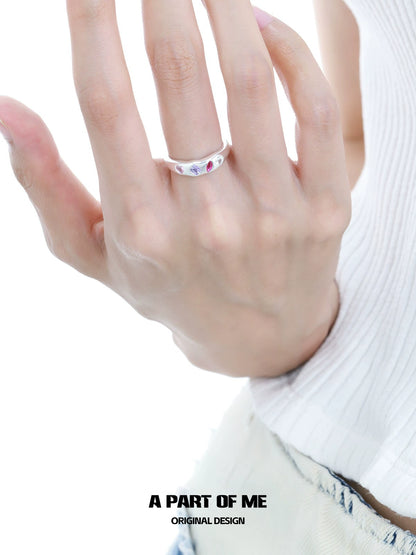 A hand wearing a rainbow zircon love ring featuring colorful stones for a unique and stylish look