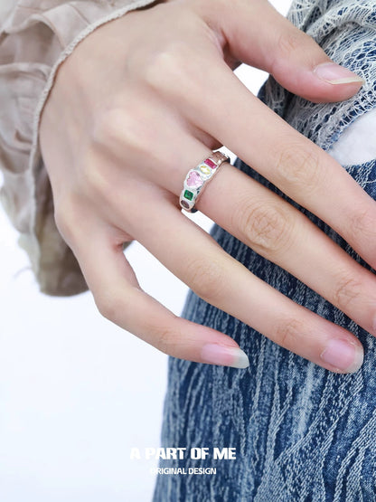 A stylish rainbow zircon love ring featured on a hand with long nails, perfect for romantic occasions