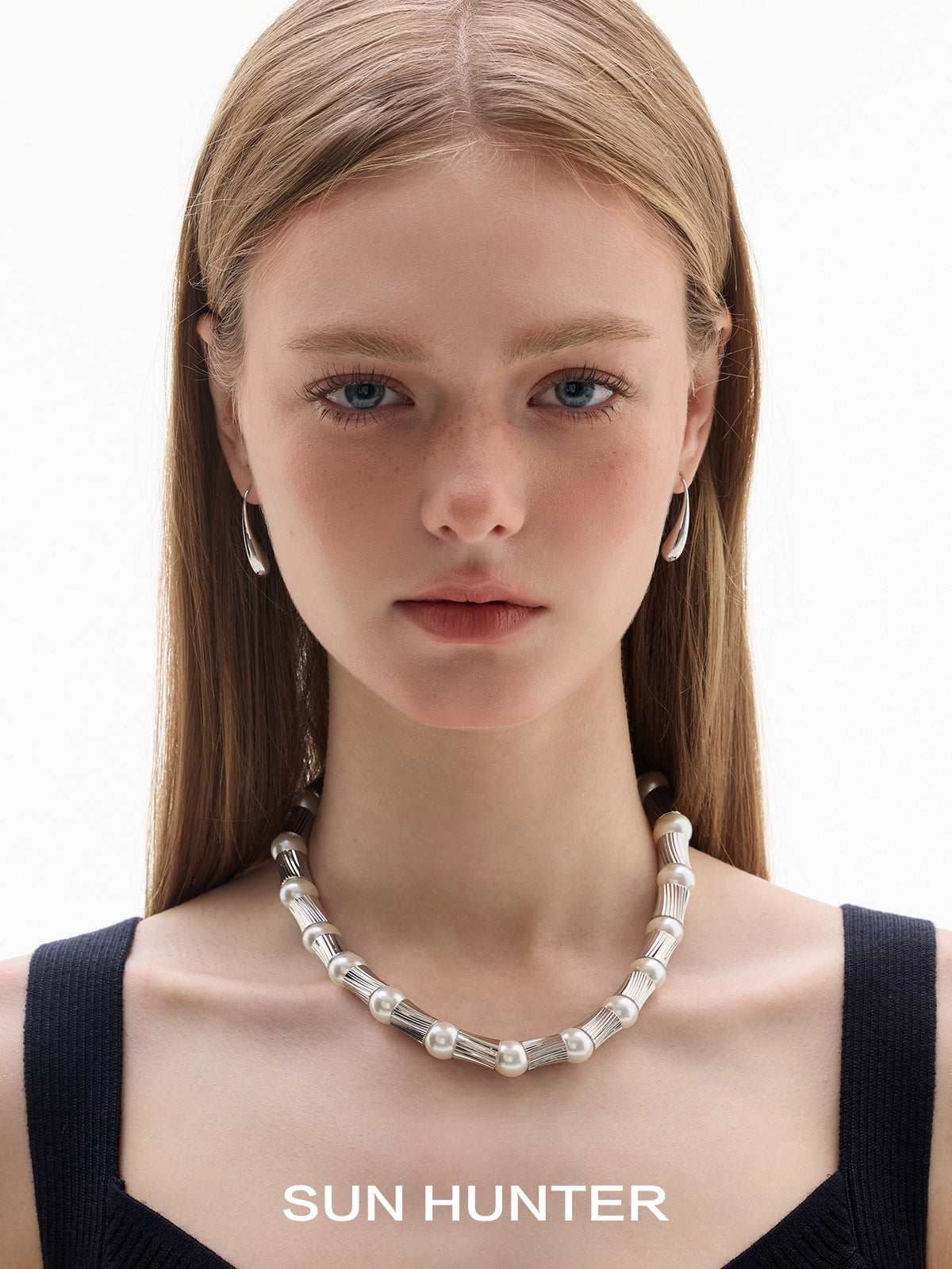 Model wearing SUN HUNTER retro metal water drop earrings with a pearl necklace, showcasing a stylish look