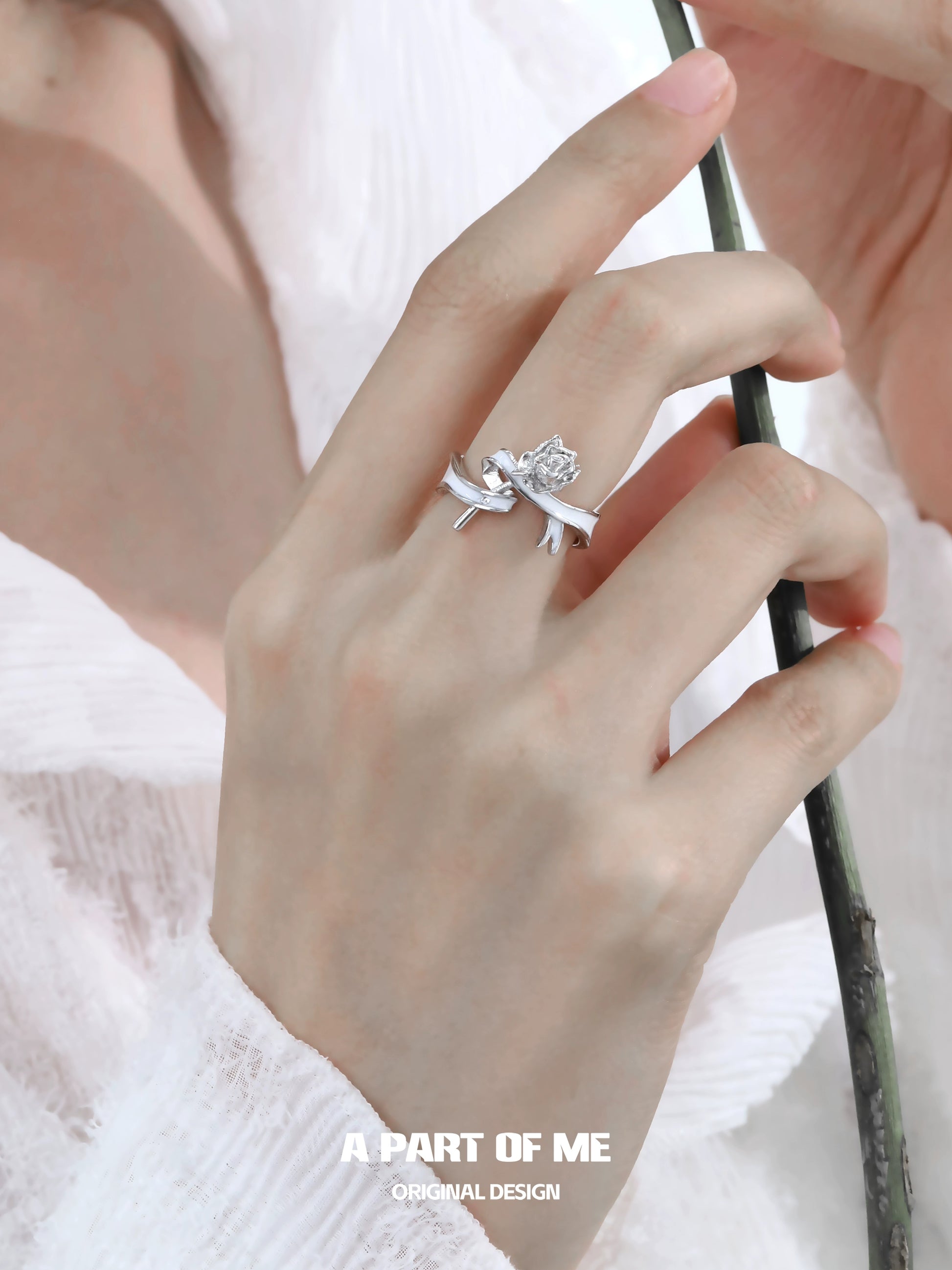 A PART OF ME rose bow silver ring displayed on a hand with a delicate floral design