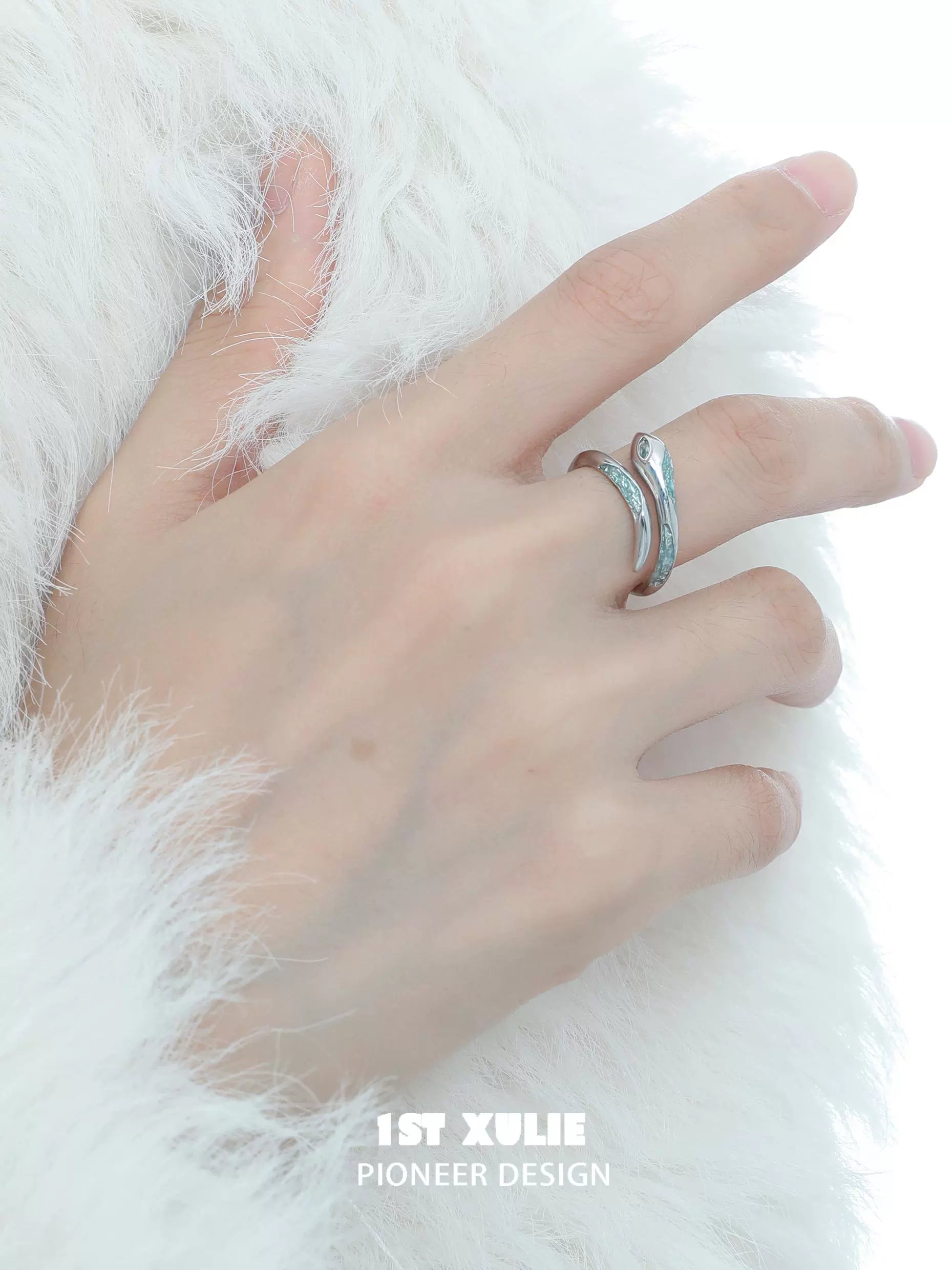 Elegant sea blue snake wrap ring on a hand with a soft white fur background