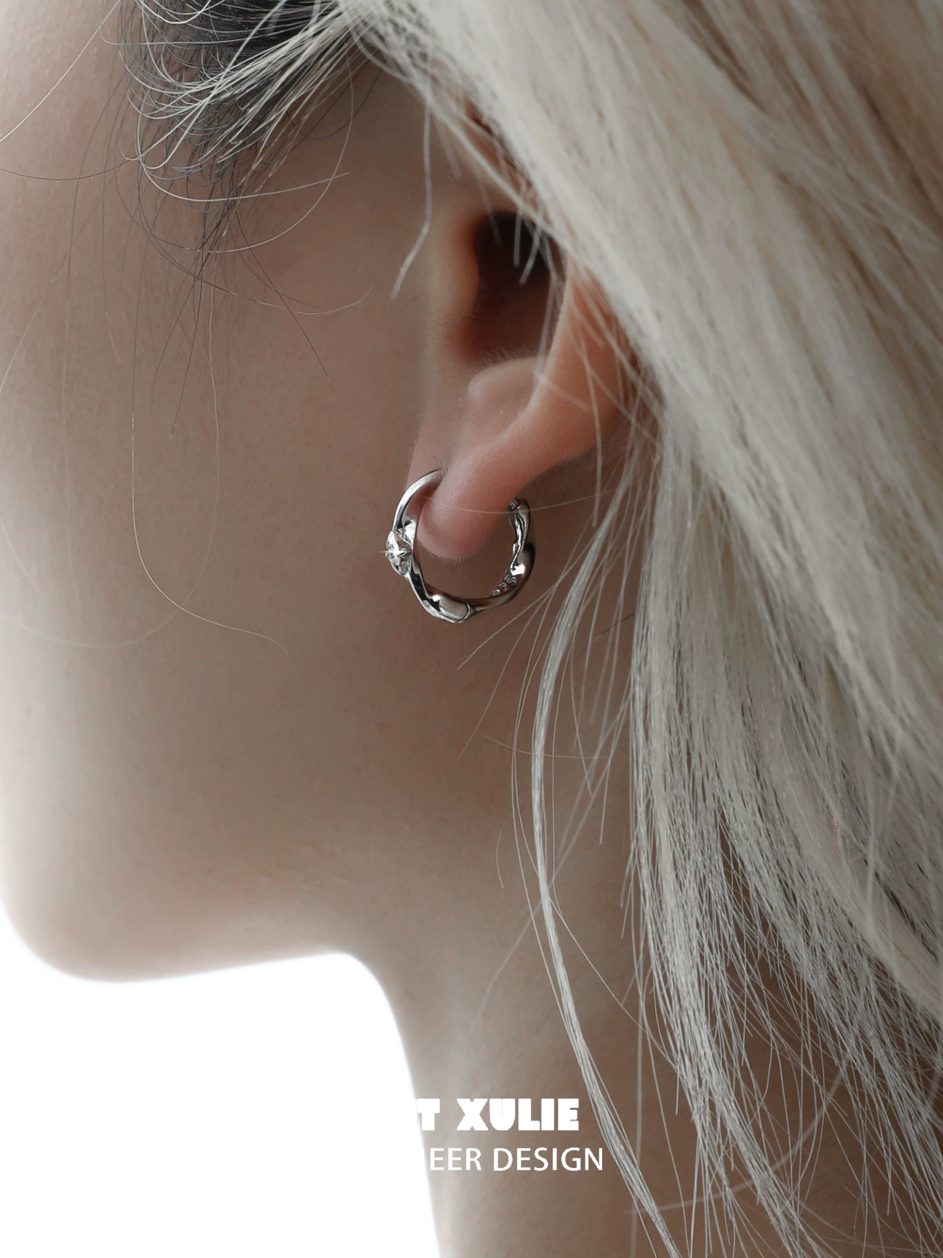 Shooting star silver earrings elegantly displayed on a model's ear with a soft hairstyle