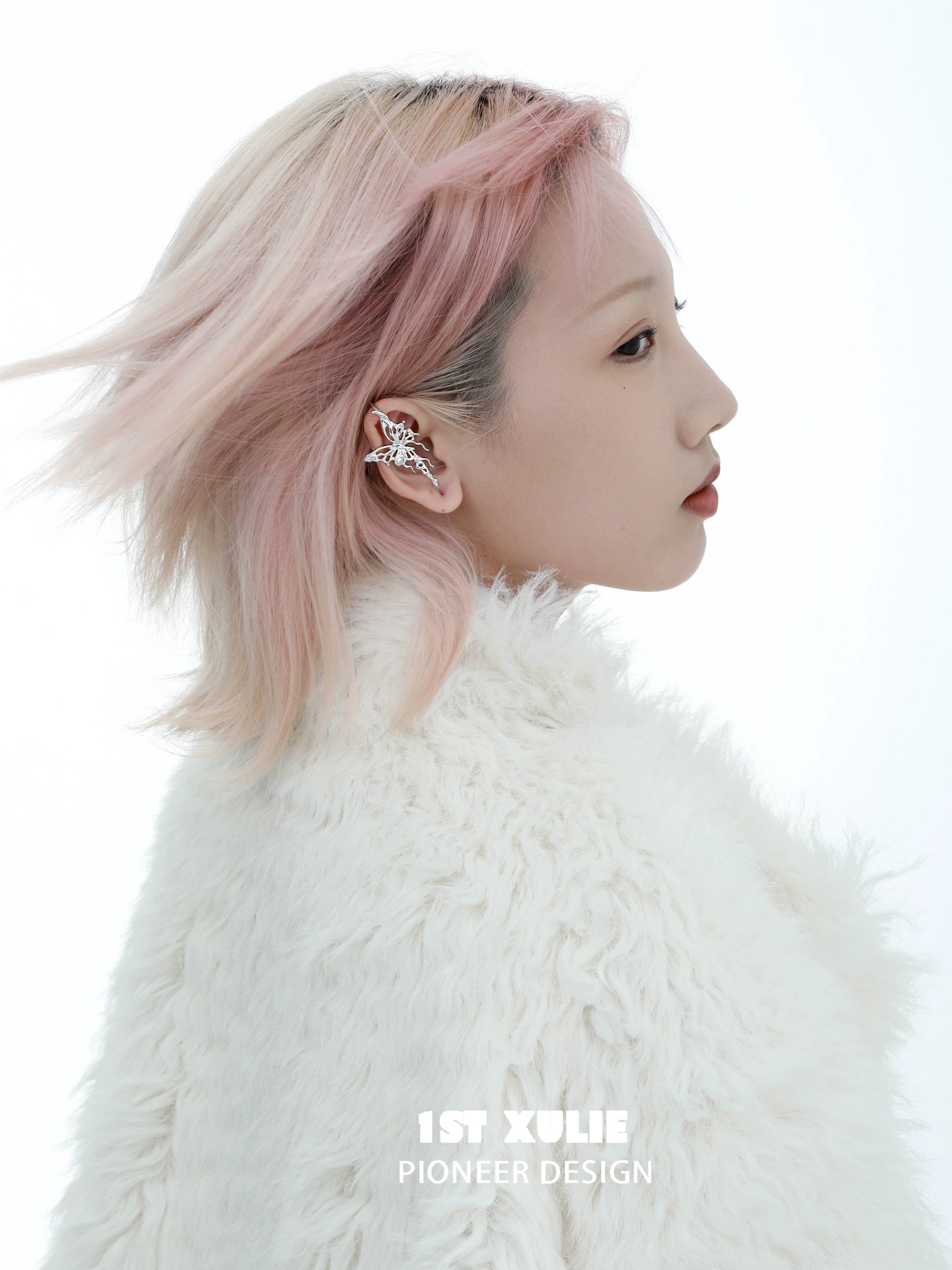 Model showcasing a silver butterfly piercing earring, styled with a fluffy white coat and soft pink hair