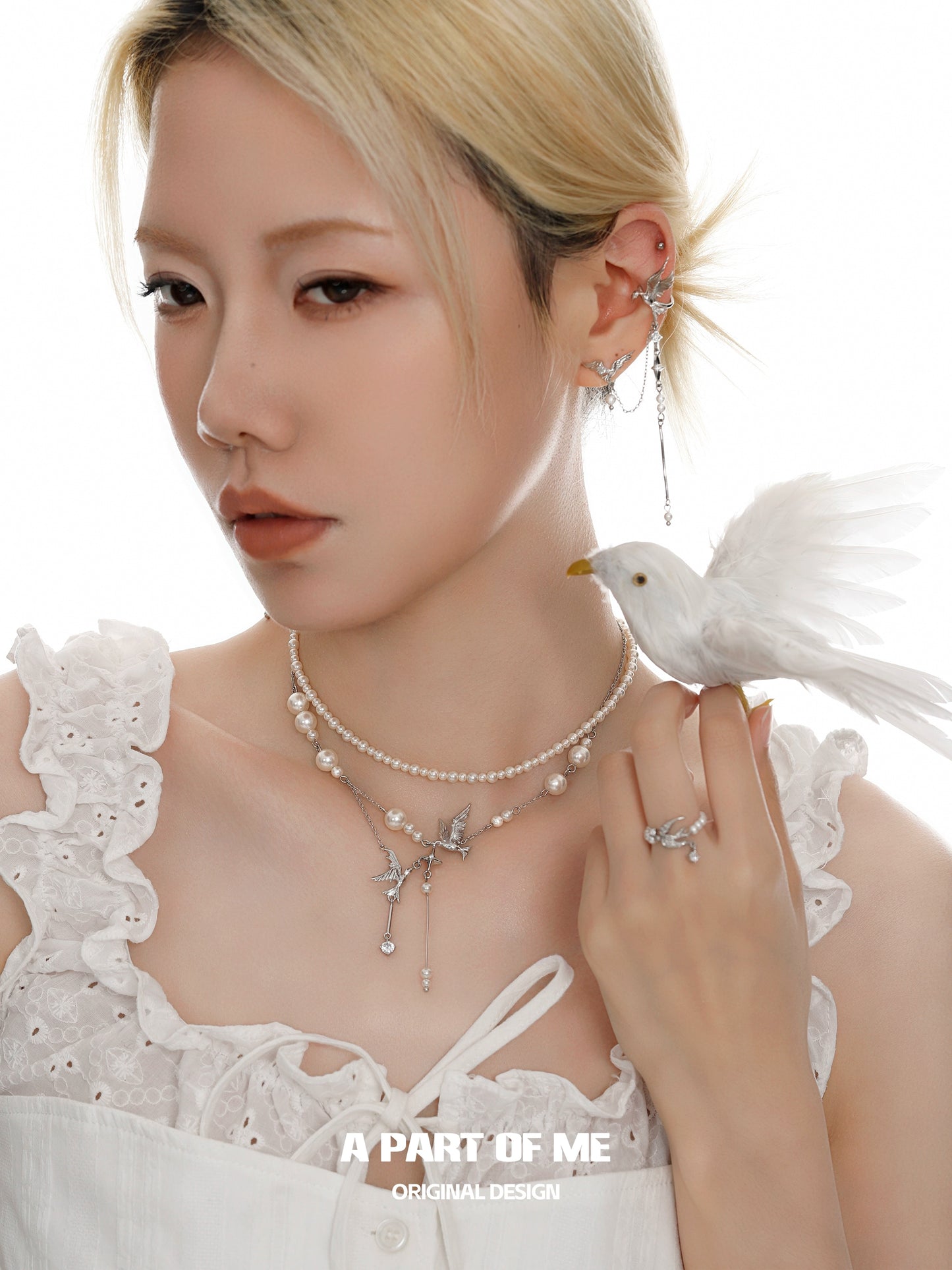 Elegant model wearing a silver pearl ring along with pearl jewelry and bird accessory