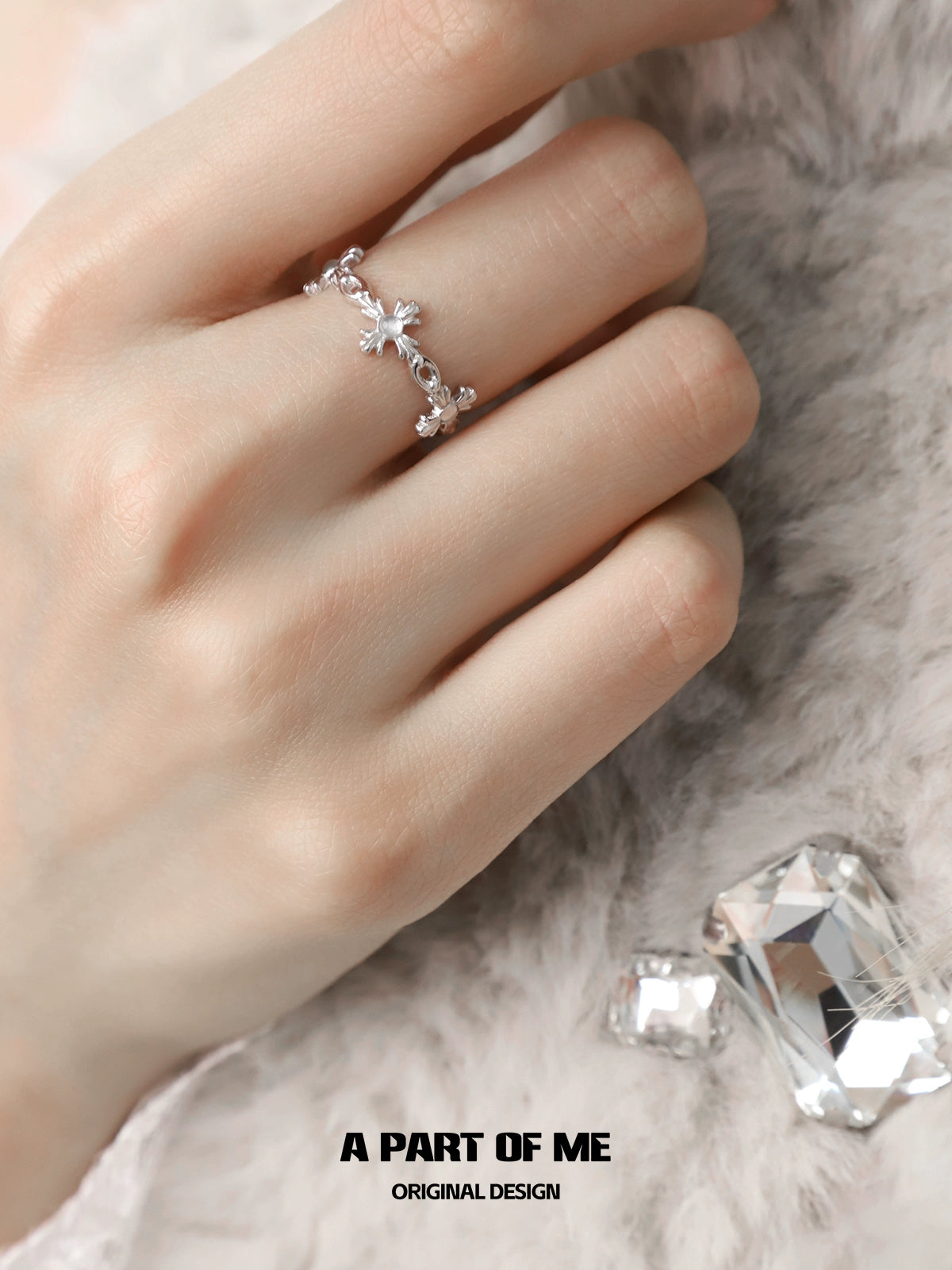 A PART OF ME snowflake cross agate ring on a hand with sparkling crystals in the background