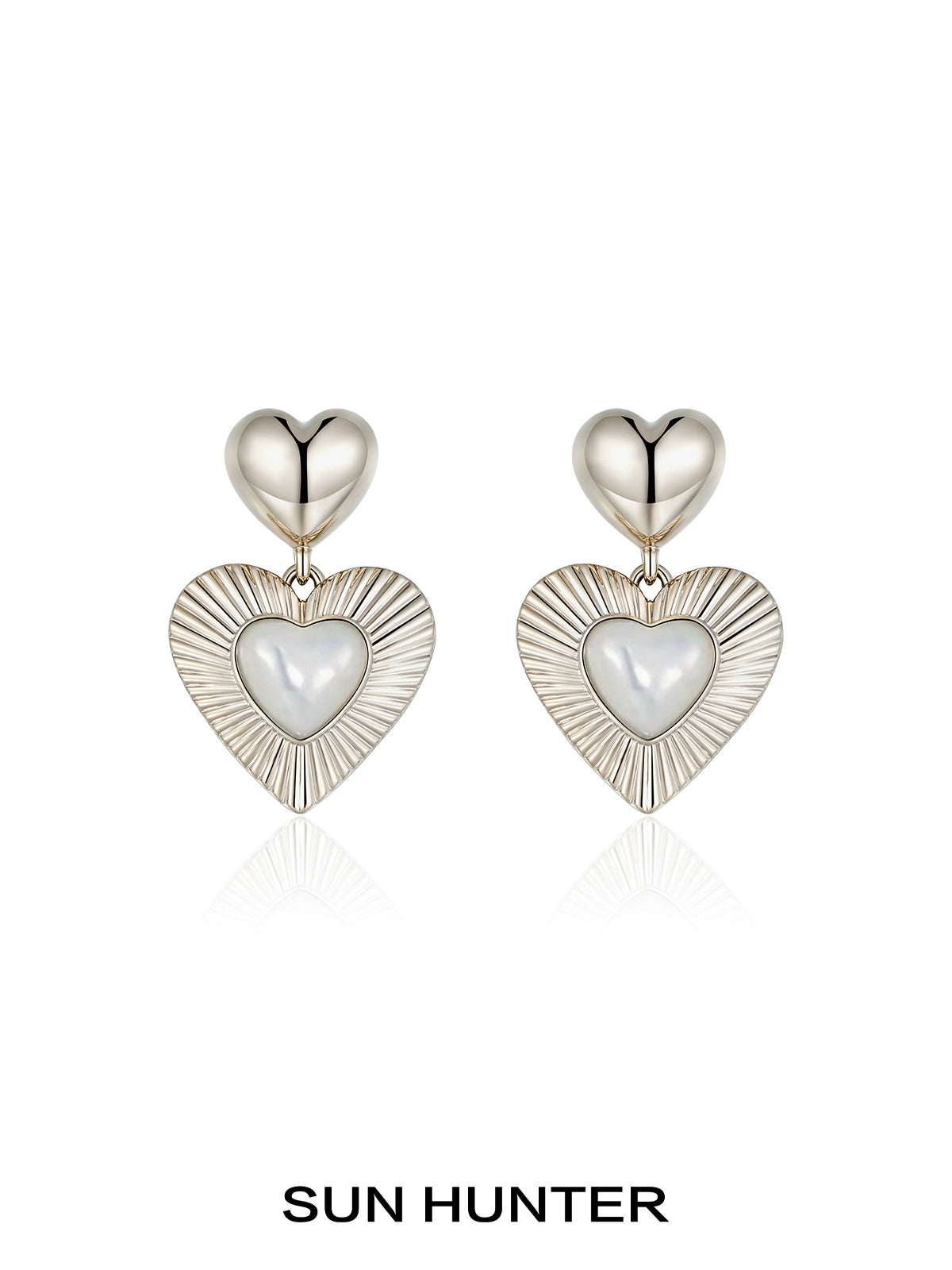 SUN HUNTER heart shaped statement earrings with a silver finish and sleek design