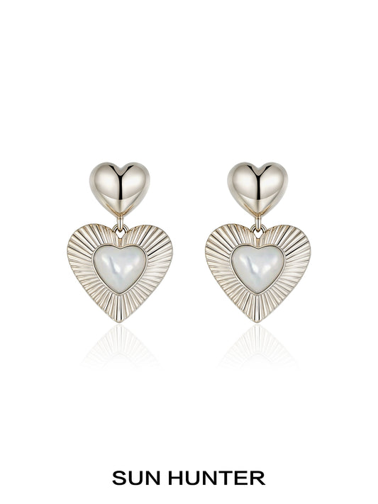 SUN HUNTER heart shaped statement earrings with a silver finish and sleek design