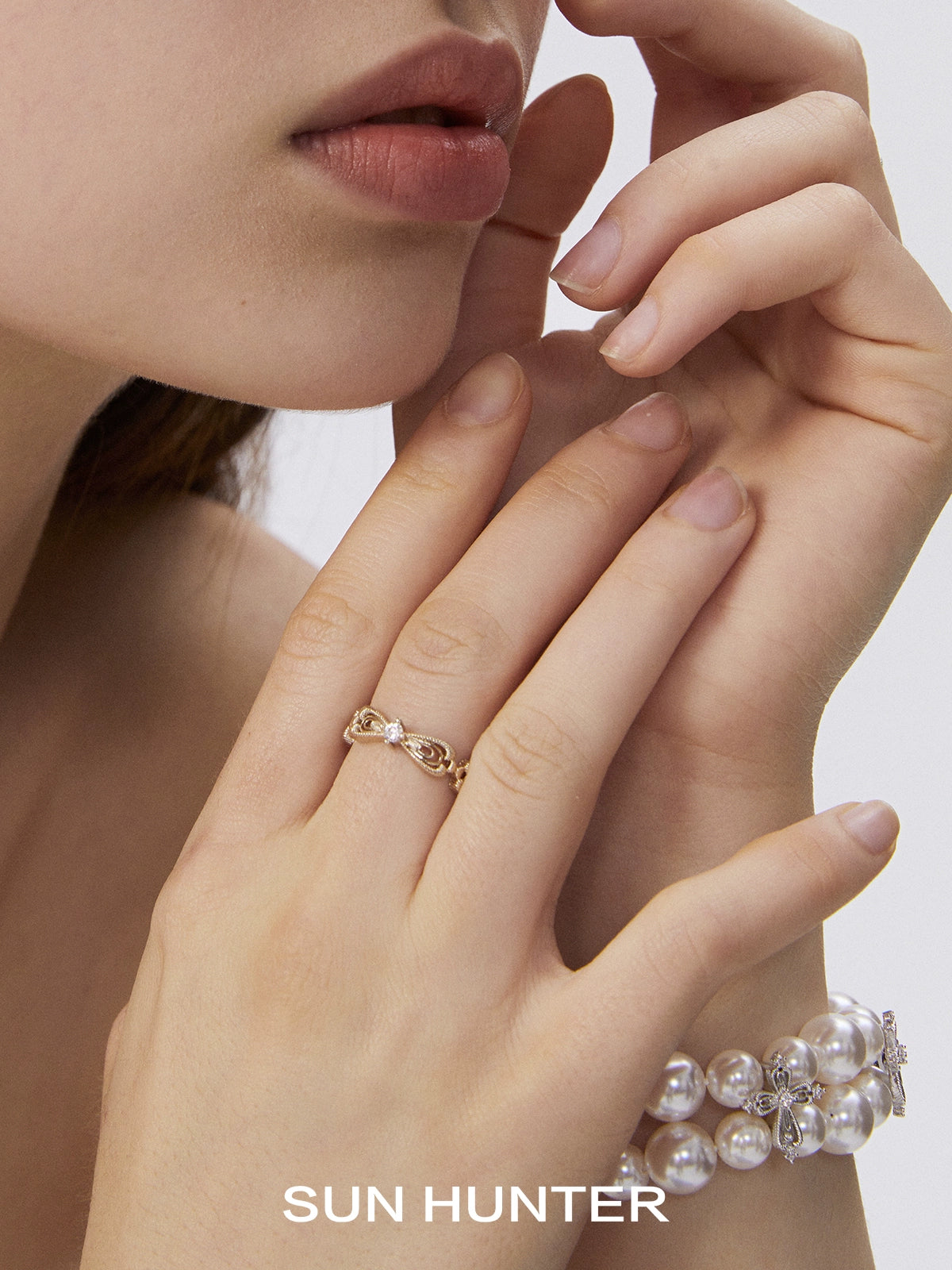 Elegant SUN HUNTER bow lace ring showcased on a model's hand with stylish bracelets