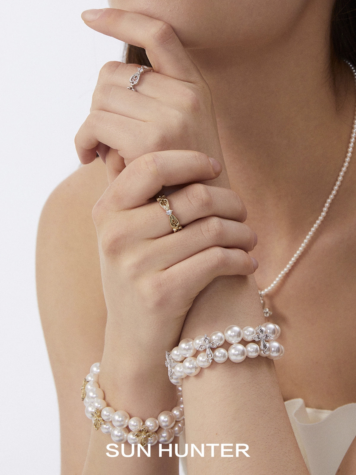 Elegant SUN HUNTER bow lace ring displayed on a model's hand with pearl bracelets