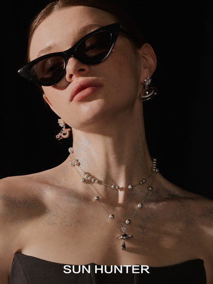 Elegant model wearing a SUN HUNTER universe planet silver necklace with intricate detailing and pearls