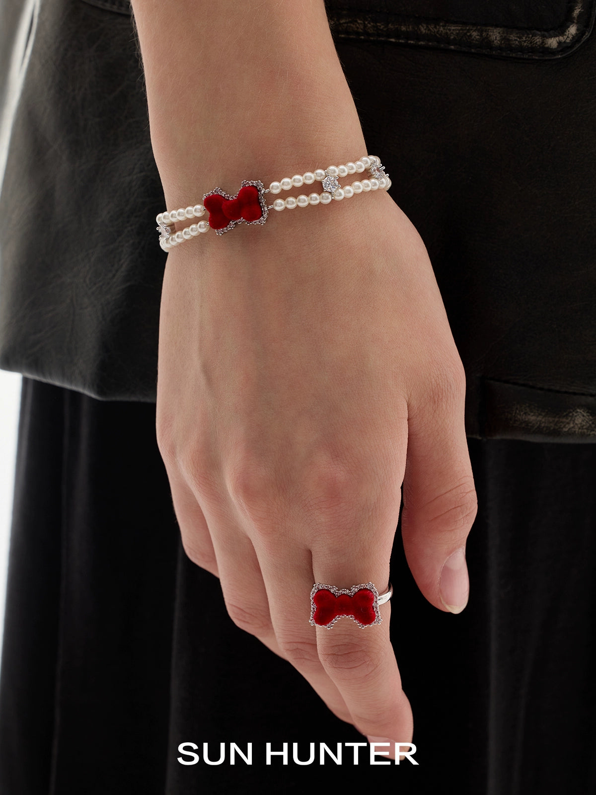 Elegant SUN HUNTER velvet butterfly heart ring worn with a pearl bracelet on a model's hand