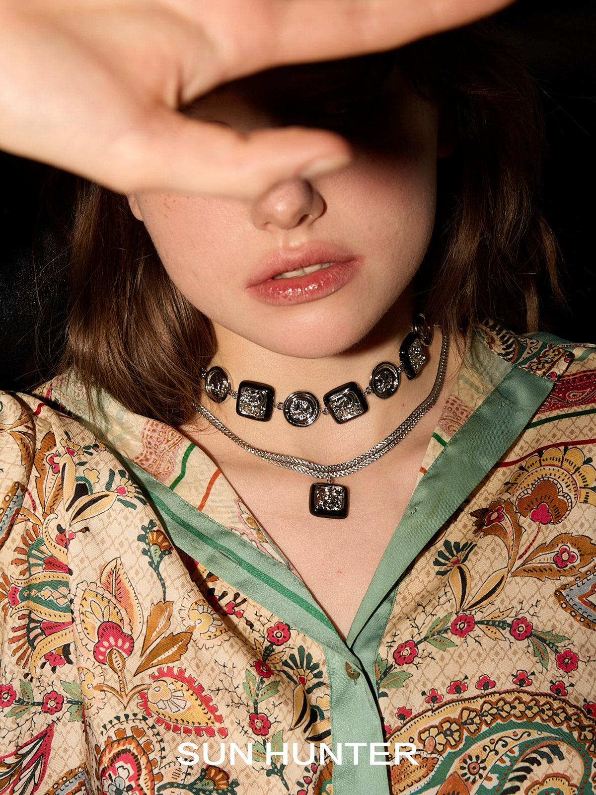 Model wearing SUN HUNTER vintage coin stud earrings with a floral-patterned blouse and layered necklaces