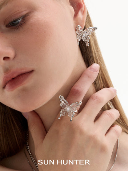 Elegant SUN HUNTER transparent butterfly earrings showcased on model's ear and hand