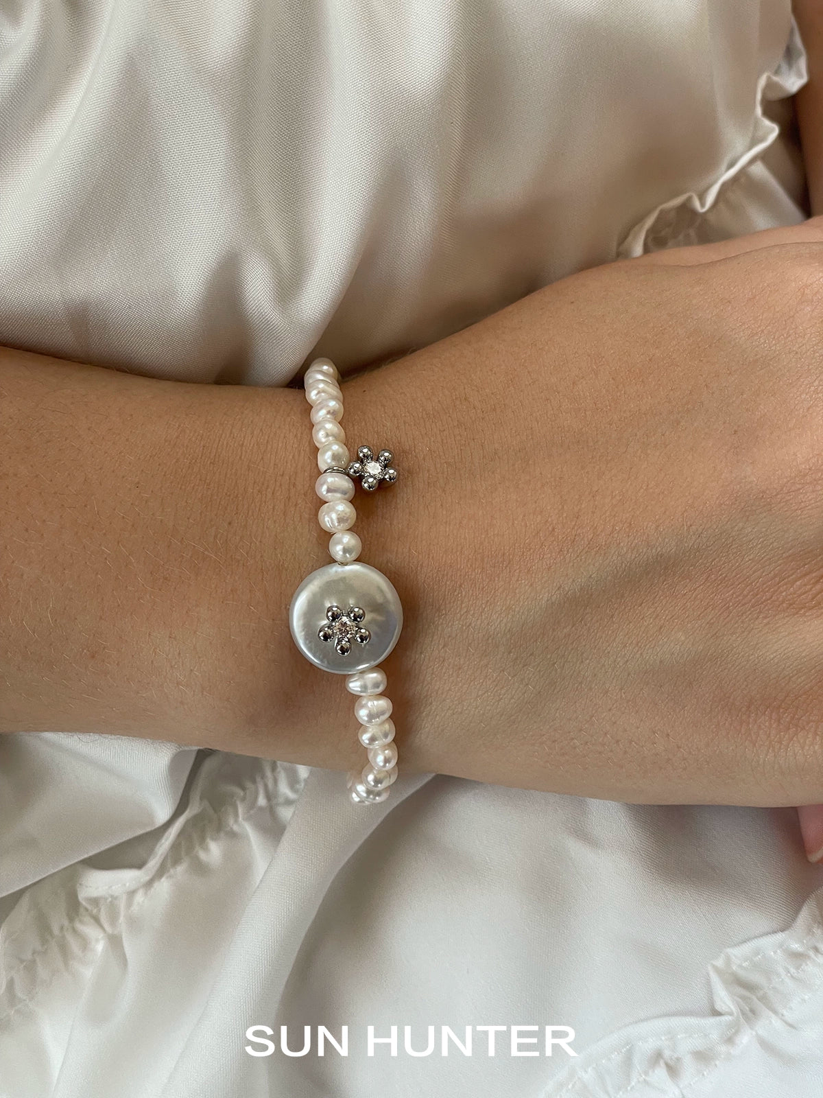 Elegant SUN HUNTER unique pearl bracelet featuring a decorative button and pearl accents