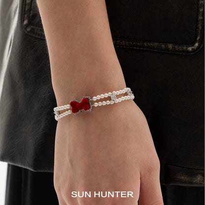 Elegant velvet bow pearl bracelet by SUN HUNTER featuring a red bow charm and pearl detailing