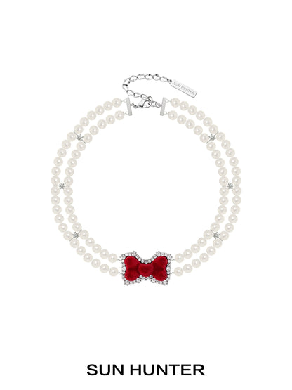 Elegant SUN HUNTER velvet bow pearl bracelet featuring a red bow and pearl beads