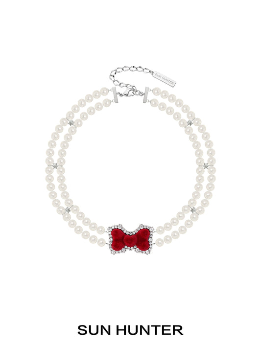Elegant SUN HUNTER velvet bow pearl bracelet featuring a red bow and pearl beads